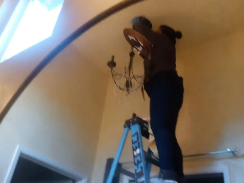 Electrician installing a chandelier in a Wilton residence